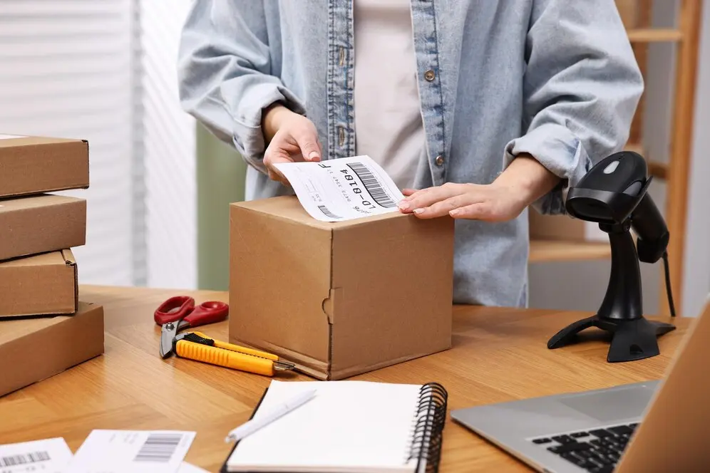 empaque-paquetes-trabajador-oficina-correos-pegando-codigo-barras-caja-mesa-madera-primer-plano_495423-86844.webp